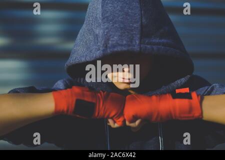 Giovane maschio mani con bande di inscatolamento davanti al viso. Il ragazzo si prepara per un allenamento boxe avvolgendo la sua mano. Boxer pronti a gettare i punzoni. Adolescente Sport, Foto Stock