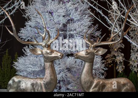 Giocattoli di natale - due figure di scintillanti cervi sullo sfondo di un bianco albero di Natale Foto Stock