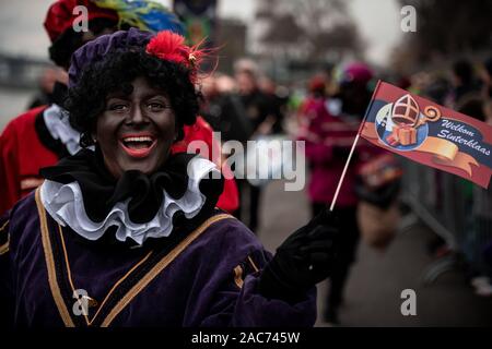 Krefeld, Germania. 01 Dic, 2019. "Zwarten Piets' saluta il pubblico. Il Sinterklaas (Nicholas) da Venlo arriva con diversi "Zwarten Piets" (Black Peter) in scia a Steiger in Krefeld in barca. Tradizionalmente, 'Zwarten Piets' distribuire caramelle ai bambini. Nei Paesi Bassi il dipinto di nero aiutanti di Sinterklaas sono ora controversa. Un paio di giorni fa vi sono state proteste con molti arresti di Apeldoorn. Credito: Fabian Strauch/dpa/Alamy Live News Foto Stock