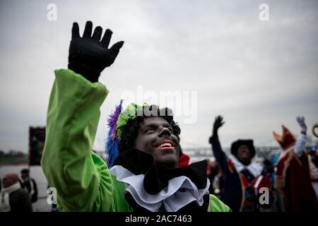 Krefeld, Germania. 01 Dic, 2019. "Zwarten Piets' saluta il pubblico. Il Sinterklaas (Nicholas) da Venlo arriva con diversi "Zwarten Piets" (Black Peter) in scia a Steiger in Krefeld in barca. Tradizionalmente, 'Zwarten Piets' distribuire caramelle ai bambini. Nei Paesi Bassi il dipinto di nero aiutanti di Sinterklaas sono ora controversa. Un paio di giorni fa vi sono state proteste con molti arresti di Apeldoorn. Credito: Fabian Strauch/dpa/Alamy Live News Foto Stock