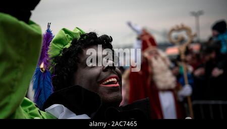 Krefeld, Germania. 01 Dic, 2019. "Zwarten Piets' saluta il pubblico. Il Sinterklaas (Nicholas) da Venlo arriva con diversi "Zwarten Piets" (Black Peter) in scia a Steiger in Krefeld in barca. Tradizionalmente, 'Zwarten Piets' distribuire caramelle ai bambini. Nei Paesi Bassi il dipinto di nero aiutanti di Sinterklaas sono ora controversa. Un paio di giorni fa vi sono state proteste con molti arresti di Apeldoorn. Credito: Fabian Strauch/dpa/Alamy Live News Foto Stock