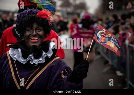 Krefeld, Germania. 01 Dic, 2019. "Zwarten Piets' saluta il pubblico. Il Sinterklaas (Nicholas) da Venlo arriva con diversi "Zwarten Piets" (Black Peter) in scia a Steiger in Krefeld in barca. Tradizionalmente, 'Zwarten Piets' distribuire caramelle ai bambini. Nei Paesi Bassi il dipinto di nero aiutanti di Sinterklaas sono ora controversa. Un paio di giorni fa vi sono state proteste con molti arresti di Apeldoorn. Credito: Fabian Strauch/dpa/Alamy Live News Foto Stock