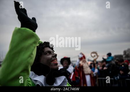 Krefeld, Germania. 01 Dic, 2019. "Zwarten Piets' saluta il pubblico. Il Sinterklaas (Nicholas) da Venlo arriva con diversi "Zwarten Piets" (Black Peter) in scia a Steiger in Krefeld in barca. Tradizionalmente, 'Zwarten Piets' distribuire caramelle ai bambini. Nei Paesi Bassi il dipinto di nero aiutanti di Sinterklaas sono ora controversa. Un paio di giorni fa vi sono state proteste con molti arresti di Apeldoorn. Credito: Fabian Strauch/dpa/Alamy Live News Foto Stock