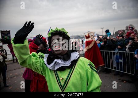 Krefeld, Germania. 01 Dic, 2019. "Zwarten Piets' saluta il pubblico. Il Sinterklaas (Nicholas) da Venlo arriva con diversi "Zwarten Piets" (Black Peter) in scia a Steiger in Krefeld in barca. Tradizionalmente, 'Zwarten Piets' distribuire caramelle ai bambini. Nei Paesi Bassi il dipinto di nero aiutanti di Sinterklaas sono ora controversa. Un paio di giorni fa vi sono state proteste con molti arresti di Apeldoorn. Credito: Fabian Strauch/dpa/Alamy Live News Foto Stock