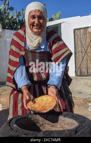 Sousse, Tunisia - 8 Novembre 2019: old Lady la cottura di un tradizionale pane arabo a Sousse in Tunisia Foto Stock