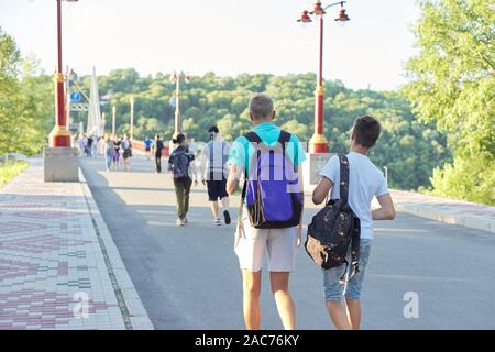 Stile di vita dei giovani maschi, adolescenti con zaini a piedi le spalle a piedi ponte sul fiume, soleggiata giornata estiva Foto Stock