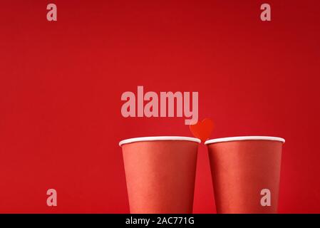 Rosso di due tazze da caffè con cuore come giovane in amore su sfondo rosso. Il giorno di San Valentino e concetto romantico Foto Stock