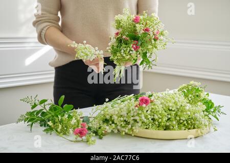 Le mani della donna fioraio rendendo bouquet di fiori rosa rose fresche il giglio della valle. La molla bouquet per matrimoni, vacanza. Fiorai, lavoro Foto Stock