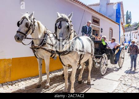 Obidos, Portogallo. Originariamente un twn fortificata ma ora una popolare destinazione turistica. I turisti a fare un giro su un carro trainato da cavalli Foto Stock