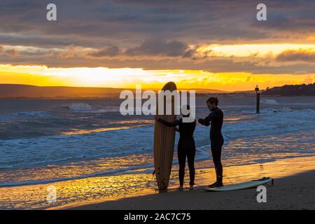 Bournemouth Dorset UK. Il 1 dicembre 2019. Regno Unito: meteo incredibile tramonto a Bournemouth Beach alla fine di un terribilmente freddo asciutto soleggiata giornata invernale. Surfers permanente sulla riva con tavole da surf al tramonto. Credito: Carolyn Jenkins/Alamy Live News Foto Stock