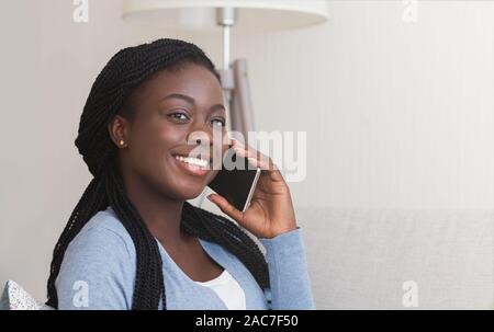 Sorridente nero donna parlando al telefono mobile a casa Foto Stock