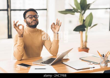 Uomo nero meditando in ufficio come affrontare lo stress Foto Stock