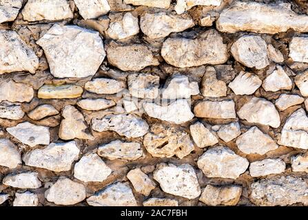 Weathered muro di pietra come creativo texture di sfondo. Le pietre naturali della muratura con cuciture irregolari. Ruvido muro di pietra texture close up Foto Stock