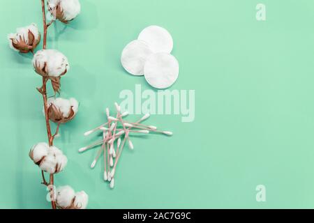 Rametto di cotone e batuffoli di cotone e piazzole di contatto su un sfondo di menta. Eco-friendly Foto Stock