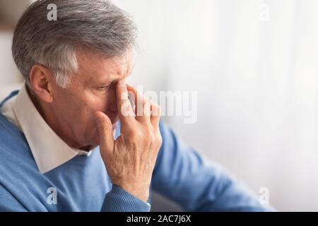 Disperato uomo anziano pensando seduto sul divano di casa Foto Stock