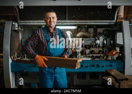 Carpenter in uniforme contiene schede, la lavorazione del legno Foto Stock