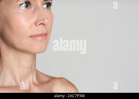 Donna di mezza età dopo trattamento anti-aging, sfondo grigio Foto Stock