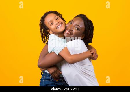 Felice nero donna che abbraccia il suo bambino adottato Foto Stock