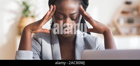 Stanco nero imprenditrice affetti da emicrania al lavoro in ufficio Foto Stock