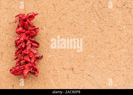 Secchi peperoncino rosso appeso sul lato esterno della parete di adobe Foto Stock