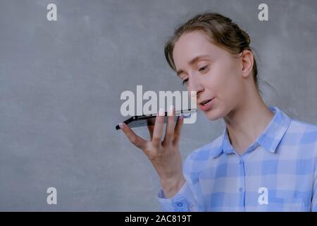 Donna che mantiene lo smartphone e con funzione di riconoscimento vocale Foto Stock