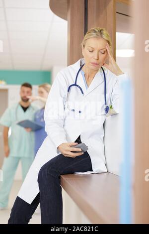 Femmina matura medico con la sua testa in mano Foto Stock