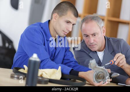 Noleggio meccanico e 2 apprendisti la riparazione di una bicicletta in officina Foto Stock