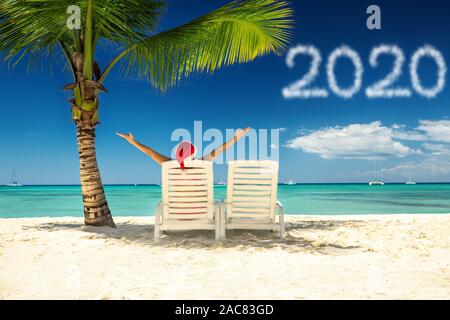 2020 Anno nuovo concetto con la donna a santa's hat rilassante sulla spiaggia tropicale. Foto Stock