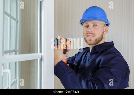 Happy builder maschio utilizza un trapano Foto Stock