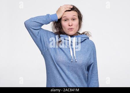 Femmina caucasica adolescente di graffiare la sua testa essendo sorpresi con le notizie. Non posso credere ai miei occhi. Studio shot Foto Stock