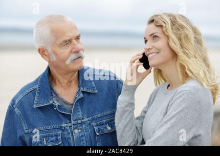 Il vecchio uomo e bellissima figlia utilizzando uno smartphone Foto Stock