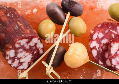 Verde e calamata olive, aglio sott'aceto e salame servito su hymalayan rosa blocco sale vista aerea Foto Stock