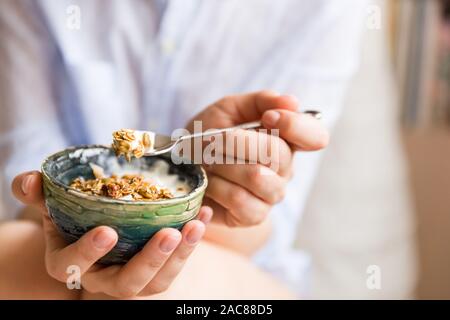 Giovane donna con muesli bowl. Ragazza mangiare cereali per la prima colazione con noci, semi di zucca, avena e yogurt nel recipiente. Ragazza con cereali fatti in casa. Un sano Foto Stock