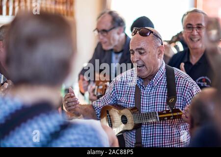 Chiusura del maschio maturo musicista appassionatamente a cantare e suonare ukelele all'interno di una barra a Garachico, Tenerife, Spagna il 23 novembre 2019 Foto Stock