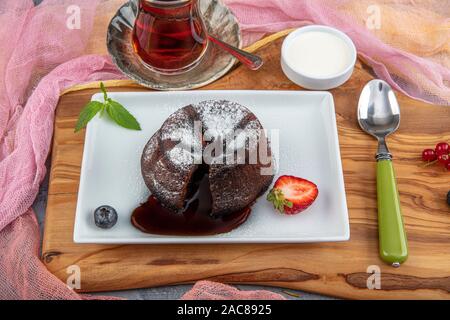 Souffle al cioccolato con centro di fusione. Il cioccolato fondente torta di lava con le fragole. Foto Stock