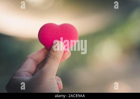 Mano di uomo asiatico tenere cuore rosa forma di bolla Foto Stock