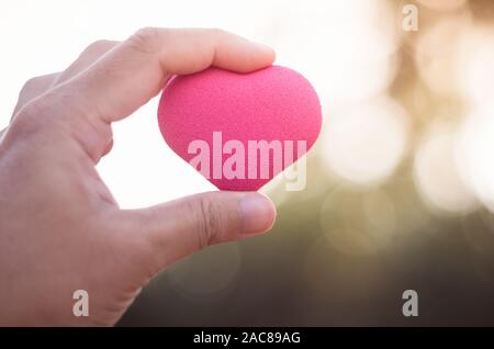 Mano di uomo asiatico tenere cuore rosa forma di bolla Foto Stock