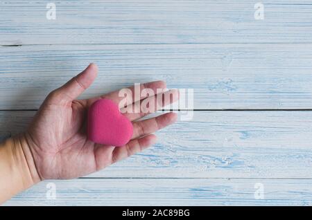 Rosa a forma di cuore in bolla uomo asiatico palm in colori pastello tono vista dall'alto Foto Stock