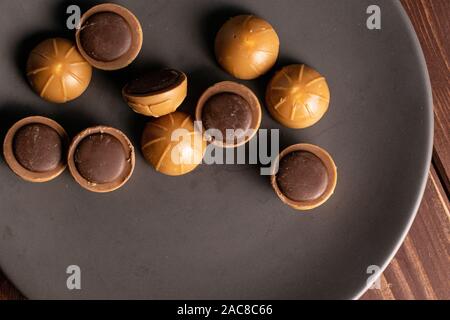 Sacco di tutto dolci caramelle mou marrone e grigio piastra ceramica flatlay su legno marrone Foto Stock