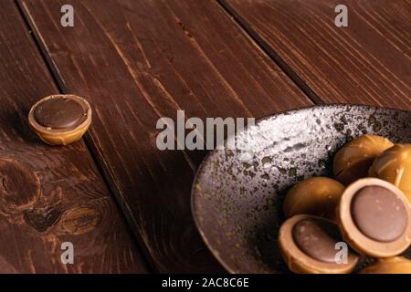 Sacco di tutto dolci caramelle mou marrone nel recipiente smaltato su legno marrone Foto Stock