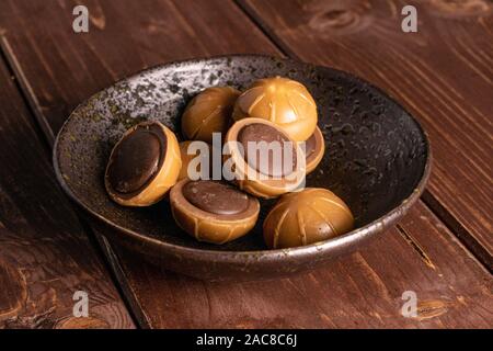 Sacco di tutto dolci caramelle mou marrone nel recipiente smaltato su legno marrone Foto Stock