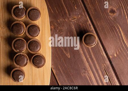 Sacco di tutto dolci caramelle mou marrone sul bambù tagliere flatlay su legno marrone Foto Stock