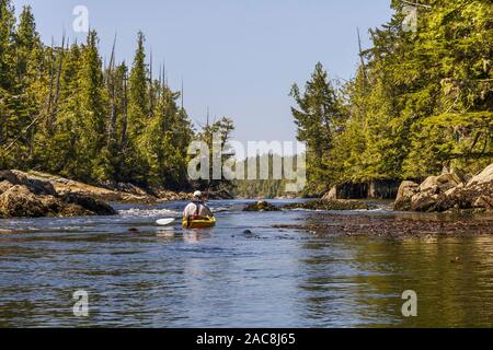 Un maschio di kayaker nella sua 50s attende al turbolento di entrata di una remota laguna di marea, considerando quando e come provare a immettere (coastal British Columbia). Foto Stock