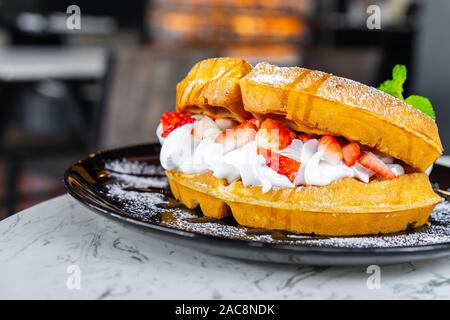 Cialde con fragole e gelato alla vaniglia sul tavolo Foto Stock