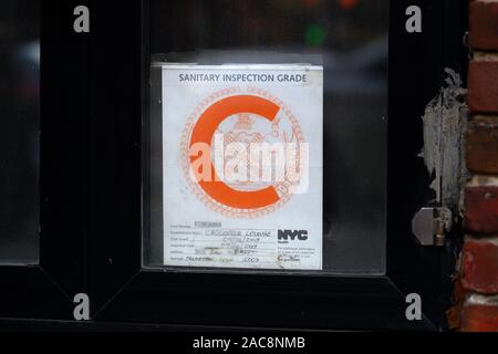 Un NYC ispezione sanitaria 'C' lettera adesivo di grado a stabilimento alimentare con le informazioni di identificazione redatto Foto Stock
