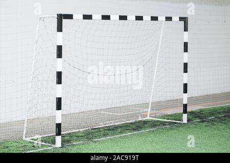 Il calcio cancelli e net contro il muro bianco su campo verde a stadio sportivo per allenamenti e partite Foto Stock