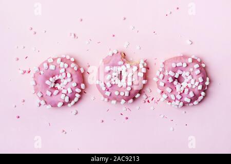 Layout creativo fatto di ciambelle rosa con marshmallows e cosparso. Concetto di cibo. Foto Stock