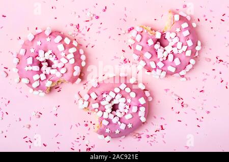 Layout creativo fatto di rosa morso ciambelle con marshmallows. Concetto di cibo. Foto Stock