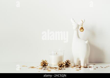 Composizione di natale con daini bianchi, candela e oro brilla. Vista frontale. Copia spazio per opere d'arte. Foto Stock