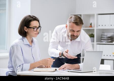 Due economisti professionisti puntando al display del notebook quando si prendono in esame le informazioni online o a lavorare al progetto Foto Stock